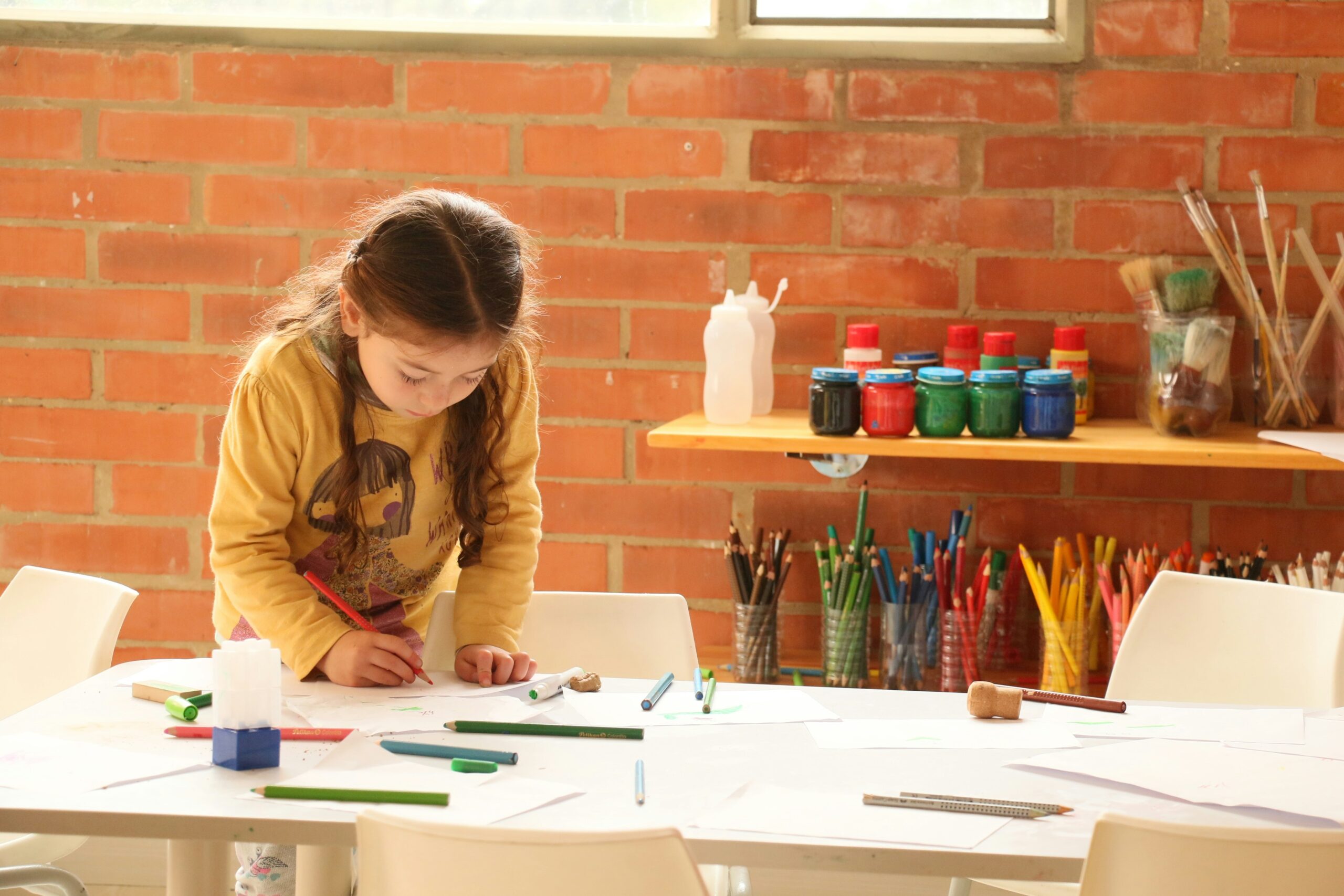 Little girl does process art on a table.